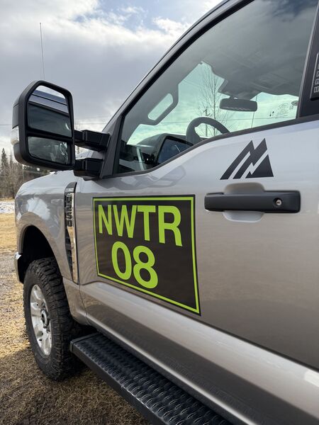 Close view of Northwest Truck Rentals fluorescent green unit decal on a silver work truck